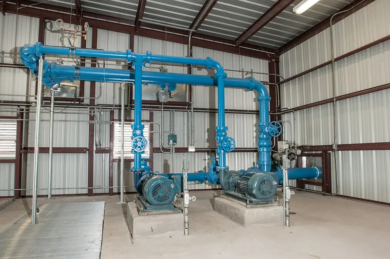 Two large electric pump motors on concrete bases with blue piping inside a metal pump building.